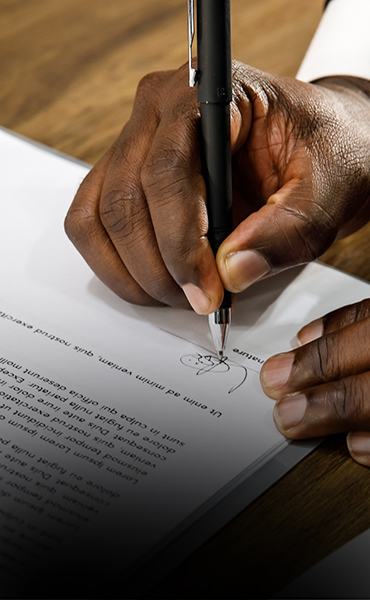 Close up and selective focus on a professional business man holding pen, signing on white paper a contract agreement.